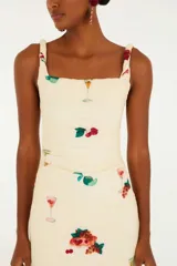 Vestido largo de tirantes con estampado de cócteles y motivos tropicales. Presenta escote cuadrado y tirantes retorcidos.