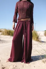 Pantalón palazzo color borgoña de lino tejido, con tiro medio, cintura elástica y cordón ajustable.