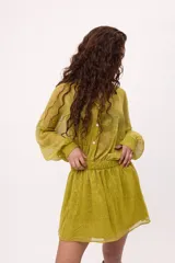 Vestido corto color verde lima, estilo camisero, confeccionado en chiffon transparente. Tiene cuello camisero, mangas largas abullonadas y elástico en la cintura.