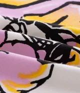 Remera blanca de algodón con cuello redondo y mangas cortas. Presenta un estampado estilo grafiti en la espalda con lettering en amarillo y rosa, y la ilustración de un perro con gorra y aerosol.