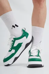 Zapatillas de cuero con combinación de colores blanco y verde, diseño moderno y suela negra.