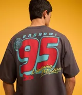 Remera gris de corte boxy, con cuello redondo y mangas cortas. Estampado frontal con logo de la película Cars, una copa y un auto.