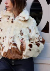 Tapado corto de piel sintética color crema con manchas marrones, con cuello clásico, cierre frontal y bolsillos laterales.