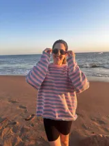 Sweater de tejido de punto con rayas horizontales anchas en tonos rosa claro y celeste/azul pálido. Presenta un corte holgado y cuello redondo.