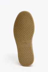 Zapatillas deportivas blancas con suela marrón en contraste y detalle de estampado animal en la parte trasera.