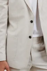 Saco beige de corte clásico, con solapas de muesca, cierre de dos botones y bolsillos laterales con solapa.