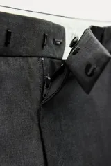 Pantalón de vestir gris oscuro de tiro bajo, con trabillas en la cintura, bolsillos delanteros y traseros, raya planchada y pierna recta.