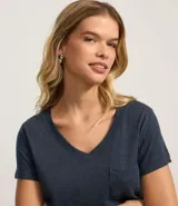 Blusa blanca de algodón con cuello en V, manga corta y bolsillo frontal.