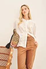 Camisa blanca de voile con rayas finas, corte amplio, cartera con botones y bordado de flores en el frente.