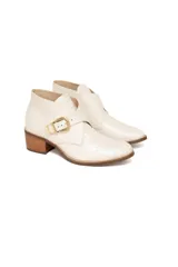 Bota corta color blanco hueso con textura de cocodrilo, taco de madera y hebilla dorada.