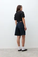 Bermuda de jean color azul oscuro, de corte recto y largo hasta la rodilla.