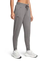 Pantalón de jogging Under Armour color gris con logo en la pierna izquierda, cintura elástica con cordón ajustable, bolsillos laterales con cierre y tobillos ajustados.