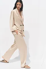 Pantalón de tiro alto color beige con cintura elástica ajustable con cordones, bolsillos delanteros y pernera ancha.
