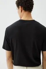 Remera negra de punto texturizado, corte regular, cuello redondo y mangas cortas.