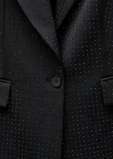 Blazer negro con pequeños apliques brillantes, cuello con solapa, cierre con un botón, dos bolsillos delanteros con solapa, forro interior y corte recto.