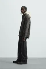 Sobrecamisa de hombre con corte relaxed fit, confeccionada en tejido de algodón acolchado con estampado a cuadros en tonos marrón, negro y beige. Tiene cuello solapa, manga larga con puños abotonados, bolsillo tipo parche en el pecho, aberturas laterales en el bajo y cierre frontal con botones a presión.