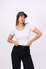 Remera corta de punto canalé color rosa, con cuello redondo y botones decorativos.