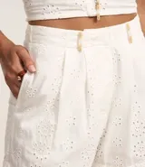 Short corto de laise de algodón con cintura fija, trabillas con abalorios, cierre tradicional, pliegues y estampa floral.