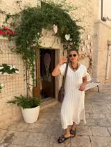 Vestido largo color beige, de tejido calado, escote en V, manga corta y corte holgado.