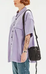 Camisa de manga corta color lavanda con doble bolsillo y ojal delantero con solapa en uno de ellos. Tiene calce oversize y está realizada en tejido plano suave al tacto.
