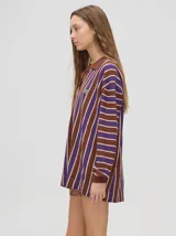 Chomba de corte oversize con cuello camisero, a rayas verticales en color marrón, lila y blanco. Tiene un logo bordado en el pecho y puños en color marrón.
