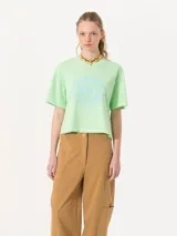 Remera verde claro de algodón pima, corte holgado, mangas cortas, cuello redondo y tajos laterales. Estampa frontal con texto y logo bordado en la espalda.