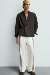 Pantalón de lino color crudo con rayas verticales negras, corte relaxed fit, cintura elástica ajustable con cordón, bolsillos laterales y traseros.