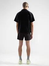 Short de baño negro con bordado de enredadera blanca en la pierna izquierda. Cuenta con cintura elástica con cordón ajustable, bolsillos laterales y bolsillo trasero con cierre. Incluye suspensor de malla fina hipoalergénico.