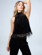 Conjunto de musculosa y pantalón en terciopelo negro, marca Julia Jordan. Blusa de cuello alto y terminación de ruedo con plumas. Pantalón con cintura elastizada.