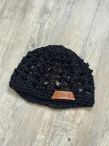 Gorro negro tejido a crochet con etiqueta de cuero con el logo de la marca.