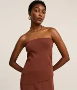 Blusa marrón sin breteles, de corte ajustado y bajo asimétrico, con textura acanalada y laterales fruncidos.