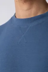 Remera de hombre color crudo, corte oversize, confeccionada en algodón grueso con textura micropanal. Diseño liso sin logos, con costura en forma de 'X' en la espalda. Ideal para un look casual y relajado.