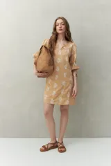 Vestido corto color beige con estampado paisley blanco. Presenta escote en V, mangas 3/4 con elástico y corte relajado.