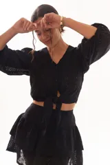 Minifalda negra con bordado inglés, cintura alta y detalle de argollas metálicas en el lateral.