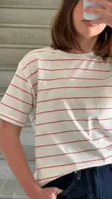 Camiseta blanca con rayas horizontales rojas y logo bordado en el pecho.