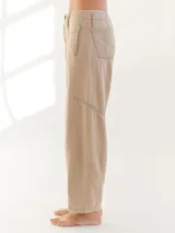 Pantalón largo color beige, tipo baggy, con costuras en verde y etiqueta turquesa en la parte trasera.