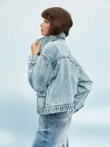 Campera de jean celeste con efecto lavado, corte cropped, cuello camisero, cierre frontal con botones metálicos, cuatro bolsillos frontales con solapa y puños abotonados.