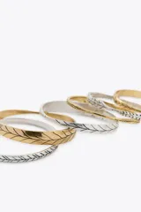 Set de pulseras rígidas doradas y plateadas con diferentes diseños labrados.