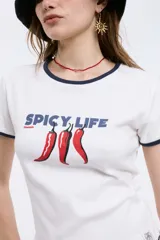 Remera blanca de algodón con cuello y mangas con ribete azul marino. Estampado frontal con la frase "Spicy Life" en azul y tres ajíes rojos.