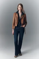 Campera de cuero ovino negra, estilo rocker, con cuello con solapas, cierre cruzado, cinturón ajustable en la cintura, charreteras en los hombros y múltiples cierres metálicos decorativos. Forro de poliéster.