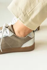 Championes marrones de cuero con cordones negros, puntera de charol y detalles dorados.