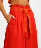 Pantalón acampanado de lino color celeste, con bolsillos, cinturón bordado y pliegues delanteros.