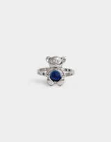 Anillo plateado con forma de oso y piedra azul en el centro.