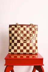 Bolso tipo tote de cuero tejido a mano con diseño a cuadros en color negro y tostado.