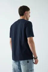 Remera azul marino de corte clásico con cuello redondo y manga corta. Estampado en el pecho con diseño geométrico en forma de triángulo que contiene una imagen de un atardecer.