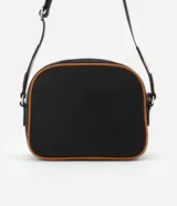 Cartera bandolera negra con detalles en marrón, confeccionada en poliéster certificado Grs y poliuretano. Presenta un aplique metálico triangular, asa larga ajustable y cierre por cremallera.