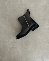 Botín marrón de cuero vacuno, con caña media, cierre lateral y suela de goma.