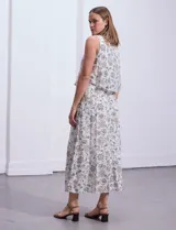 Vestido largo sin mangas, con estampado a rayas verticales en tonos beige, marrón y blanco. Tiene escote redondo y corte a la cintura con punto smock.
