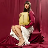 Mochila color amarillo con textura matelaseada, bolsillo frontal con cierre vertical, asa de mano y correas regulables.
