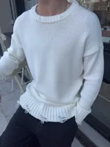 Sweater de hilo blanco roto, de corte holgado, con cuello redondo y mangas largas. Presenta detalles rotos en cuello, puños y ruedo.